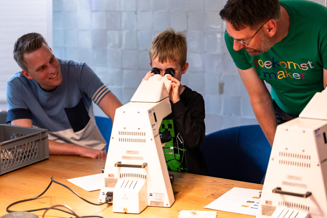 Kind kijkt door een microscoop bij de toekomstmakers